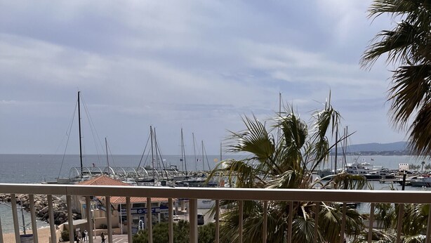 A wooden table and chairs on a balcony with a view of a marina and boats. - The Capitole, Studio 26m2, air-conditioned, sea view, balcony, WIFI, parking for 2 adults and 2 children (Fréjus)