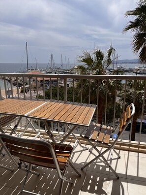 Ein Holztisch mit Stühlen auf einem Balkon mit Blick auf eine Marina und Boote.