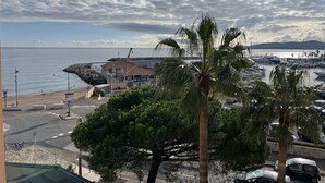 A coastal marina with boats, a building with a red roof, and palm trees. - The Capitole, Studio 26m2, air-conditioned, sea view, balcony, WIFI, parking for 2 adults and 2 children (Fréjus)