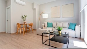 Una sala de estar moderna con un sofá, una mesa de centro, una mesa de comedor con sillas y una lámpara de pie.