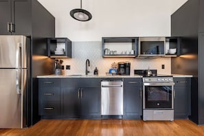 A modern kitchen with dark cabinetry, stainless steel appliances, and a central island. - 2Br Rare Find! Rooftop w/ Skyline Views the Mayfair (New Orleans)