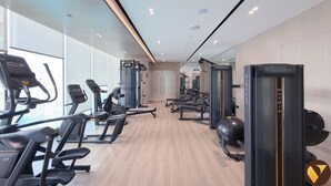 Ein Fitnessraum mit Laufbändern, Kraftgeräten und einer Spiegelwand.