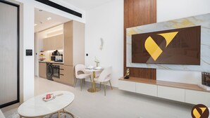 Ein modernes Wohnzimmer mit Essbereich, einer Küche im Hintergrund und einem großen abstrakten Gemälde an der Wand.