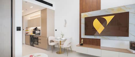 Un salon moderne avec un coin repas, une cuisine à l’arrière-plan et une grande peinture abstraite au mur.