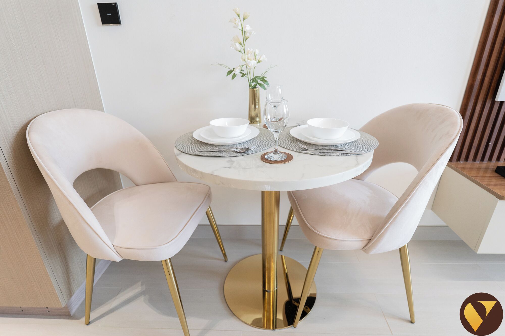 Un coin repas avec une table ronde, deux chaises et un vase rempli de fleurs.