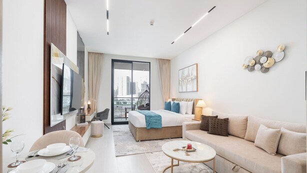 Ein modernes Hotelzimmer mit einem großen Bett, einer Couch, einem Essbereich mit Tisch und Stühlen sowie Blick auf die Stadt durch das Fenster.