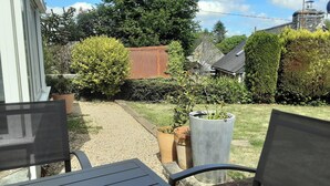 A garden with a gravel path, potted plants, and a metal fence. - Cottage 'Le Gîte D’Ambre' with Private Garden and Wi-Fi (Poullaouen)