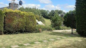 A grassy yard with a stone wall, a satellite dish, and a lamp post. - Cottage 'Le Gîte D’Ambre' with Private Garden and Wi-Fi (Poullaouen)