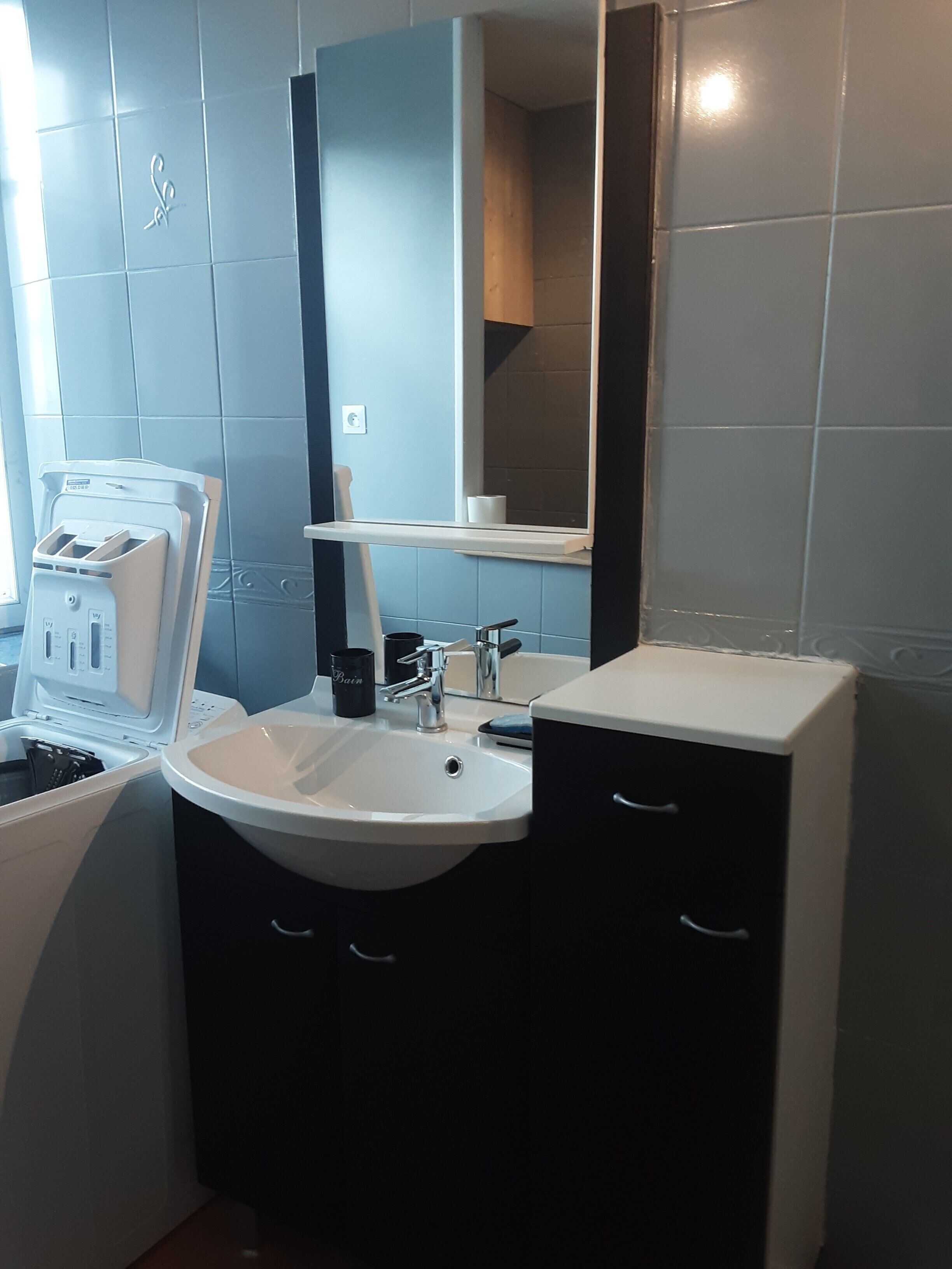 Un baño con lavamanos, espejo y toallero.