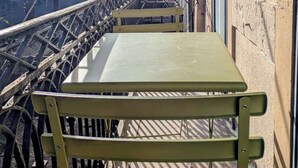 Un banco verde en un balcón con vistas a un puente y montañas.