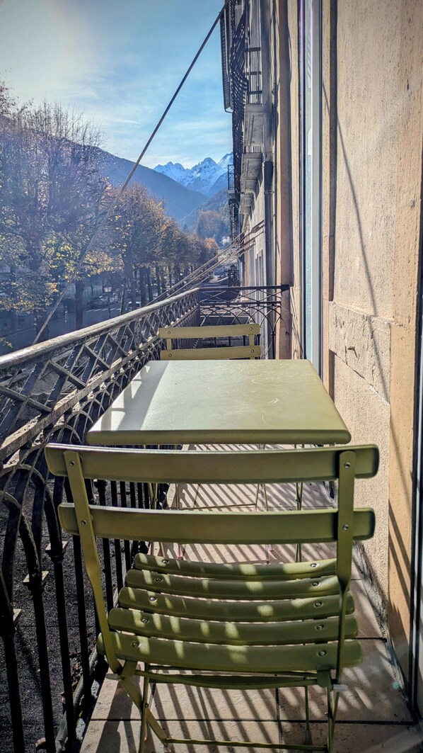 A green bench on a balcony overlooking a bridge and mountains.