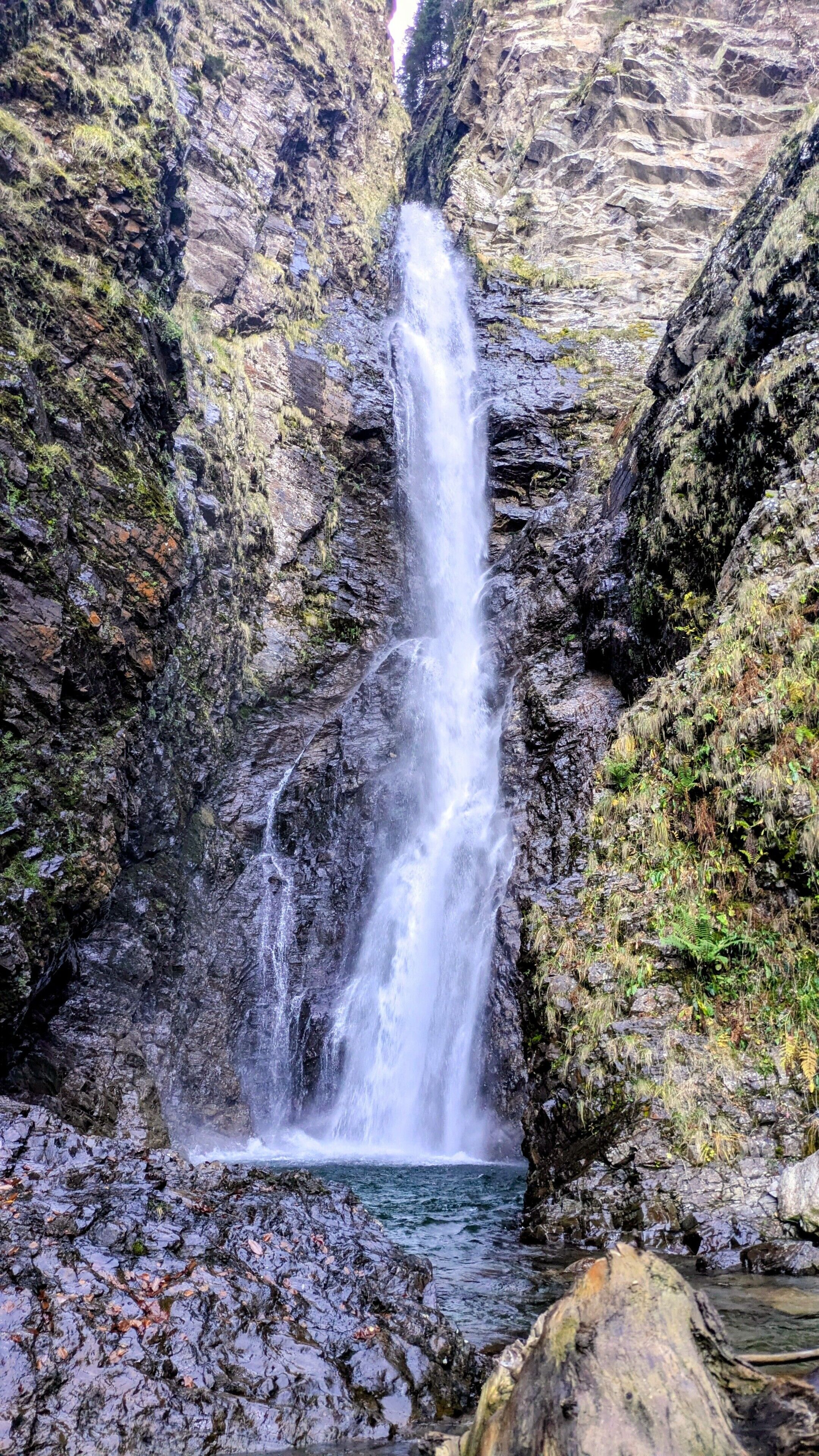 A waterfall in a rocky gorge with water flowing down a steep cliff.