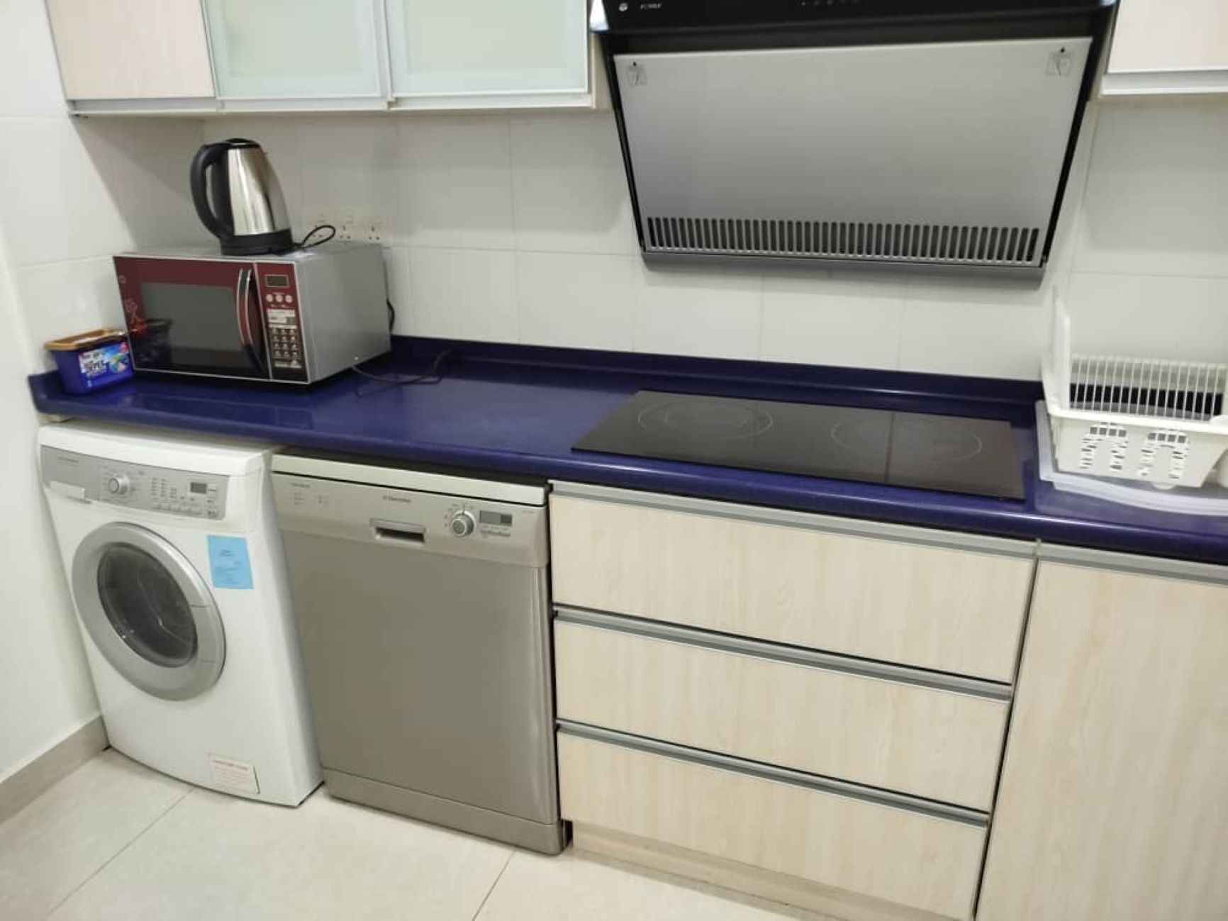 A compact kitchen with a microwave, kettle, and dishwasher.