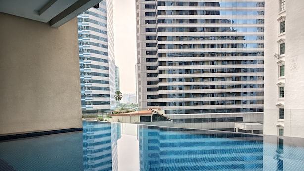 Une piscine intérieure moderne, avec une eau d’un bleu cristallin, entourée d’immeubles de grande hauteur.