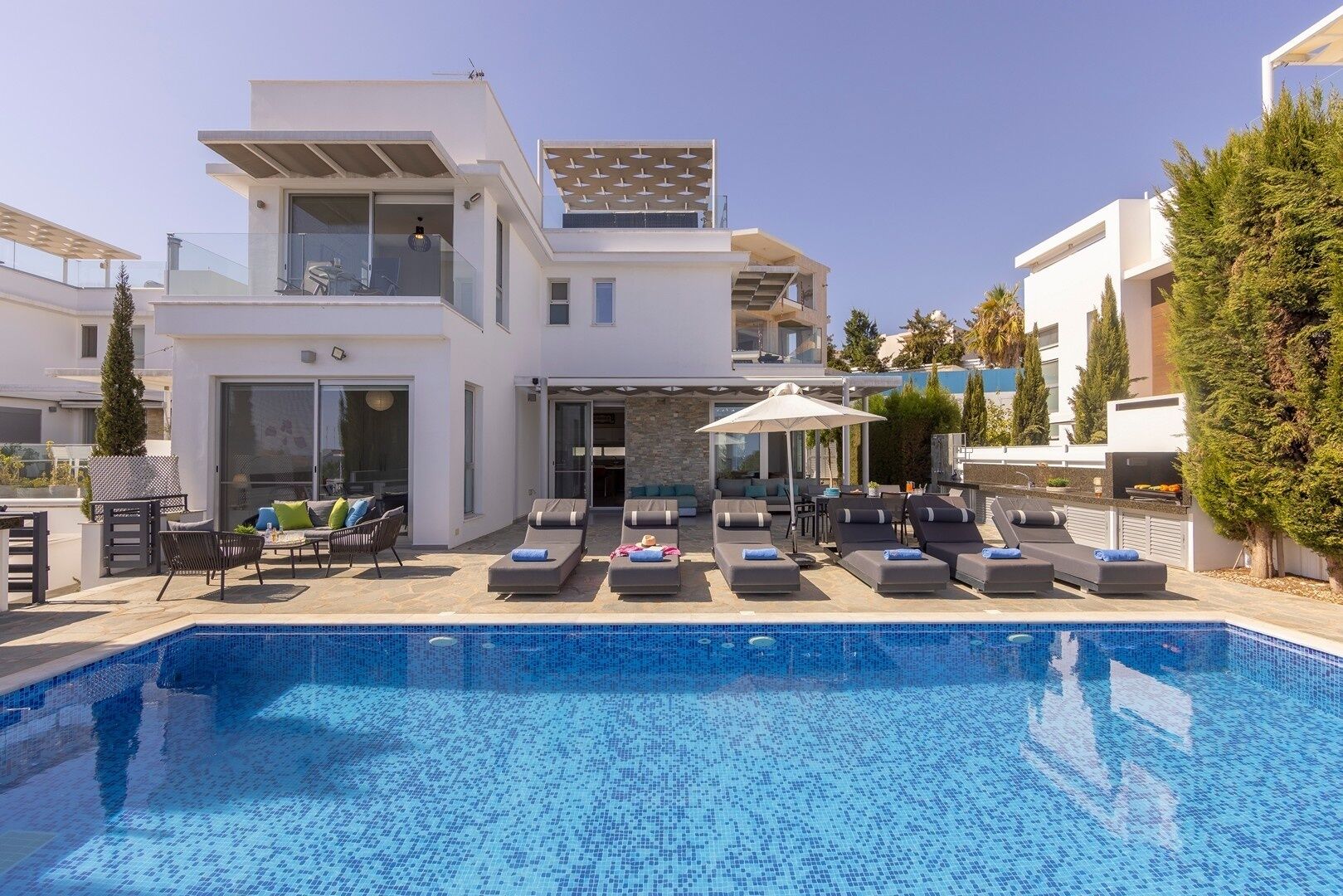 A modern poolside area with lounge chairs and a clear blue pool.