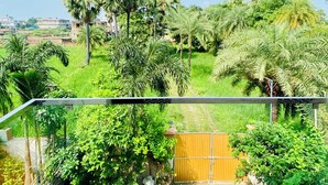 Un balcón con vistas a un jardín exuberante y edificios lejanos.