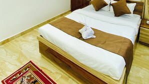Habitación de hotel con cama, ventilador de techo, ventana con cortinas y un interruptor de luz en la pared.