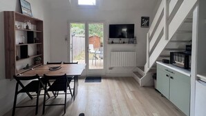 Une cuisine compacte avec un coin repas, un téléviseur fixé au-dessus du comptoir et un escalier menant à un niveau supérieur.