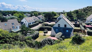 Un quartier résidentiel composé de plusieurs maisons, doté de jardins bien entretenus et bordé de collines.