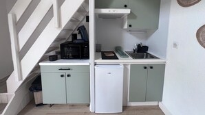 Une cuisine compacte équipée d’un four à micro-ondes, d’un grille-pain et d’un petit réfrigérateur.