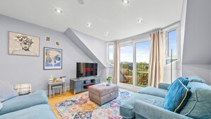 A modern living room with a TV, sofa, and a large window. - Charming Village Escape near Loch Lomond (Drymen)