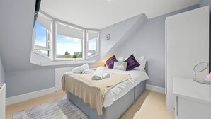 A bedroom with a large bed, a window, a bedside table, and a wardrobe. - Charming Village Escape near Loch Lomond (Drymen)