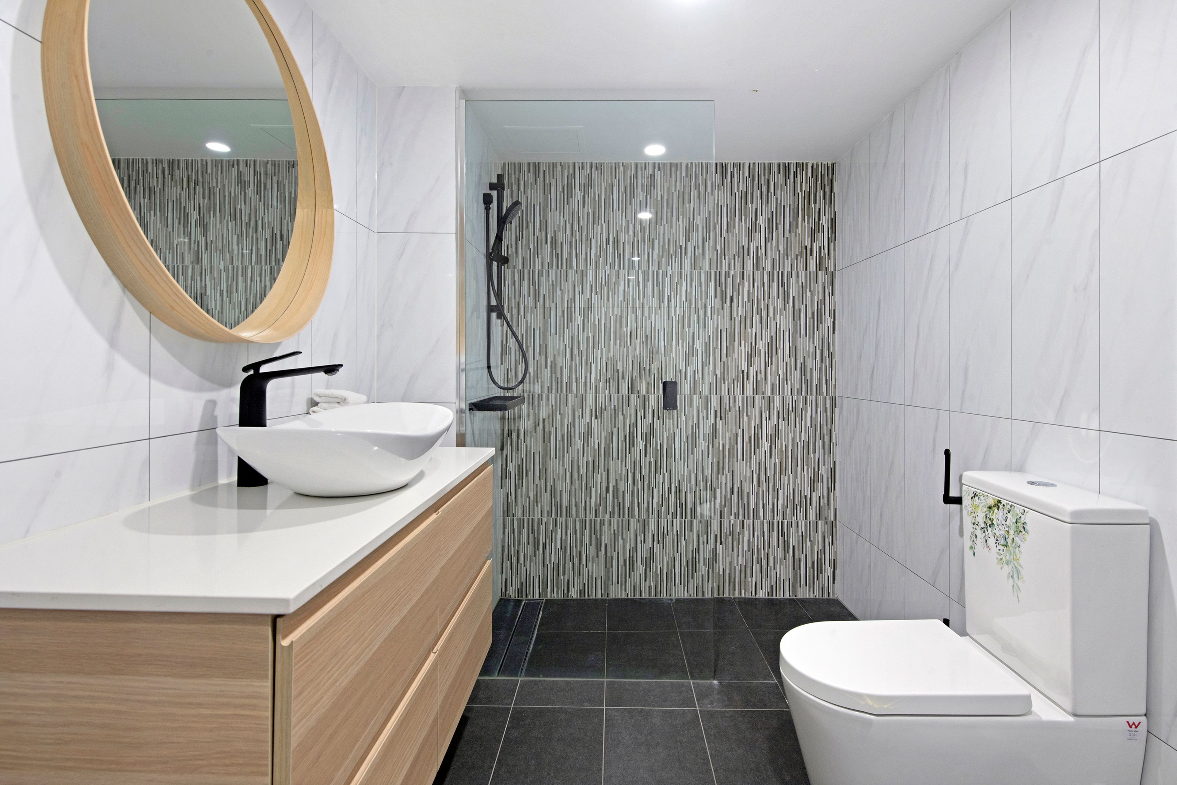 A modern bathroom with a white sink, mirror, and toilet.