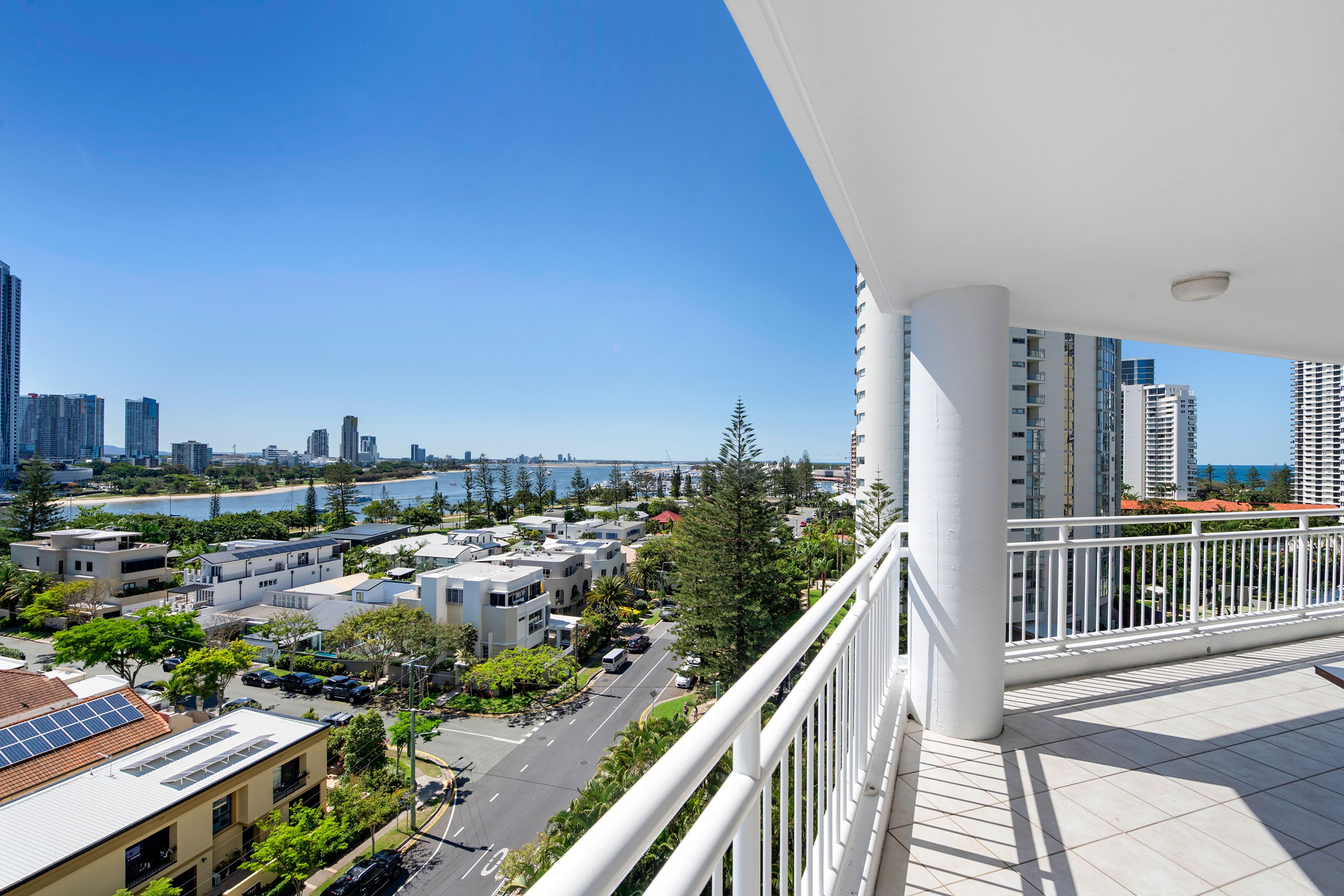 A balcony with a view of a coastal cityscape, including high-rise buildings and a beach.