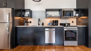 Une cuisine moderne avec des meubles de couleur sombre, des appareils en acier inoxydable et des étagères intégrées.