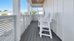 A covered porch with white railings and a wooden ceiling, featuring a white bench and a table. - Beach Please by Stay on 30a (Inlet Beach)