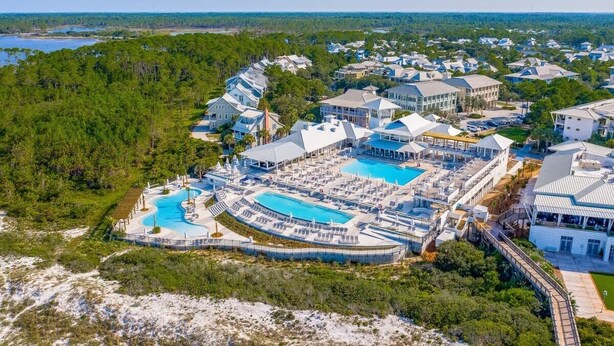 Een resort met verschillende zwembaden, een groot centraal zwembad en een strandgedeelte.