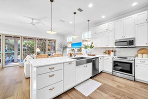 A modern kitchen with white cabinetry, stainless steel appliances, and a large island. - Blue Daze by Stay on 30a (Seacrest)