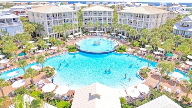 Un resort con piscina central, varios balcones y palmeras circundantes.
