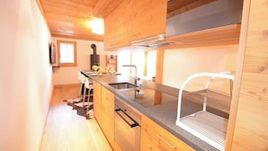Une cuisine moderne avec des meubles en bois, un évier en acier inoxydable et un meuble à vin intégré.