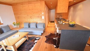Un intérieur moderne comprenant un canapé, une table basse et un coin repas avec un comptoir et des chaises.