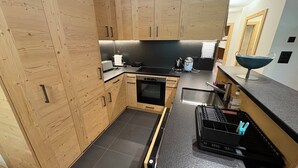 Una cucina moderna con mobili in legno, un piano di lavoro nero e un forno integrato.