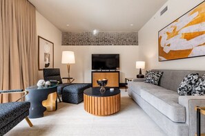 Un salon moderne comprenant un canapé, deux fauteuils, une table basse et un téléviseur.
