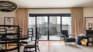 A modern living room with a dining area, large sliding glass doors leading to a balcony, and contemporary furniture. - 3BR Lavish Penthouse + Canal St Private Patio The Mayfair (New Orleans)