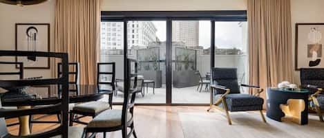 A modern living room with a dining area, large sliding glass doors leading to a balcony, and contemporary furniture.