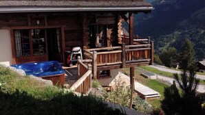 A log cabin with a wooden porch, a hot tub, and a mountain view. - Luxury chalet for 10 to 12 people with breathtaking views over the valley: 1 double bedroom with bat (Grimentz)