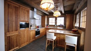 A wooden kitchen with a central island, two white chairs, and pendant lighting. - Luxury chalet for 10 to 12 people with breathtaking views over the valley: 1 double bedroom with bat (Grimentz)