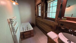 A bathroom with a wooden interior, a bathtub, a sink, and a window with a view of greenery. - Luxury chalet for 10 to 12 people with breathtaking views over the valley: 1 double bedroom with bat (Grimentz)