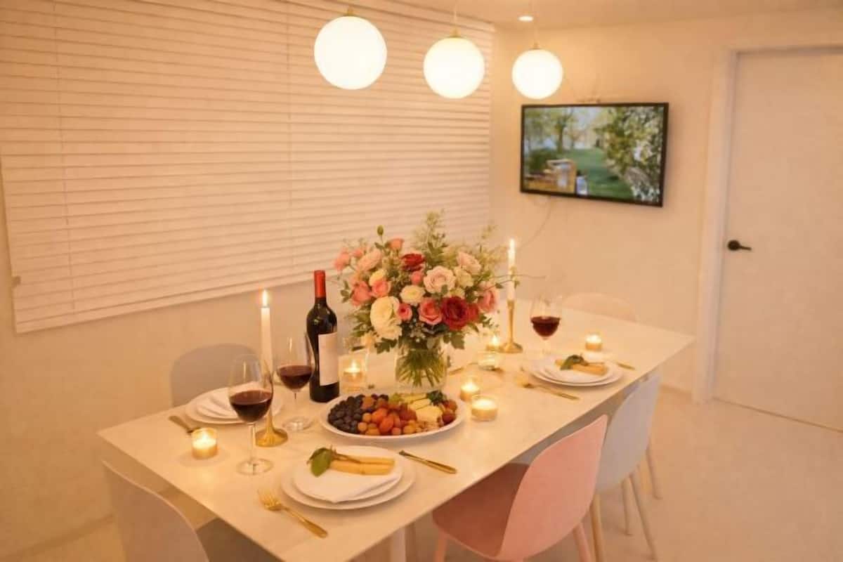 A dining table set with candles, a bottle of wine, fruit, and flowers.