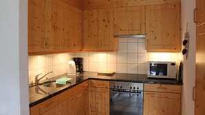 Eine Küche mit Holzausstattung, einem Spülbecken, einem Herd und einer Mikrowelle.