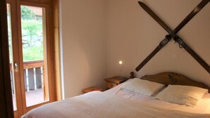 A bedroom with a wooden bed, white bedding, a nightstand, a lamp, and a large window with a view of greenery. - 3-room apartment for 6 persons : living room - kitchen with dishwasher and microwave - 1 room with 1 (Grimentz)
