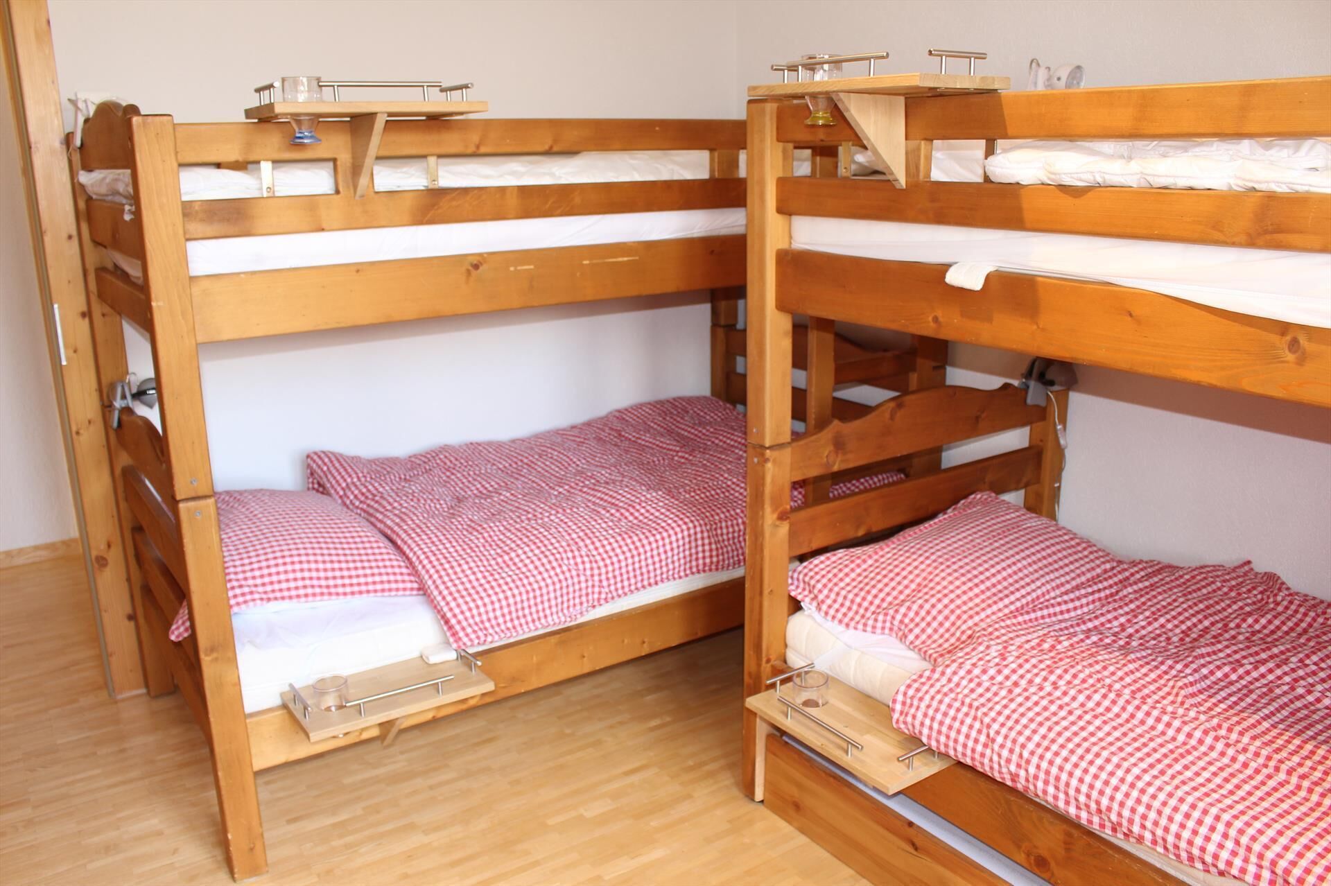 Habitación con literas de madera, dos en total, cada una con colchón y un pequeño estante en la parte superior.