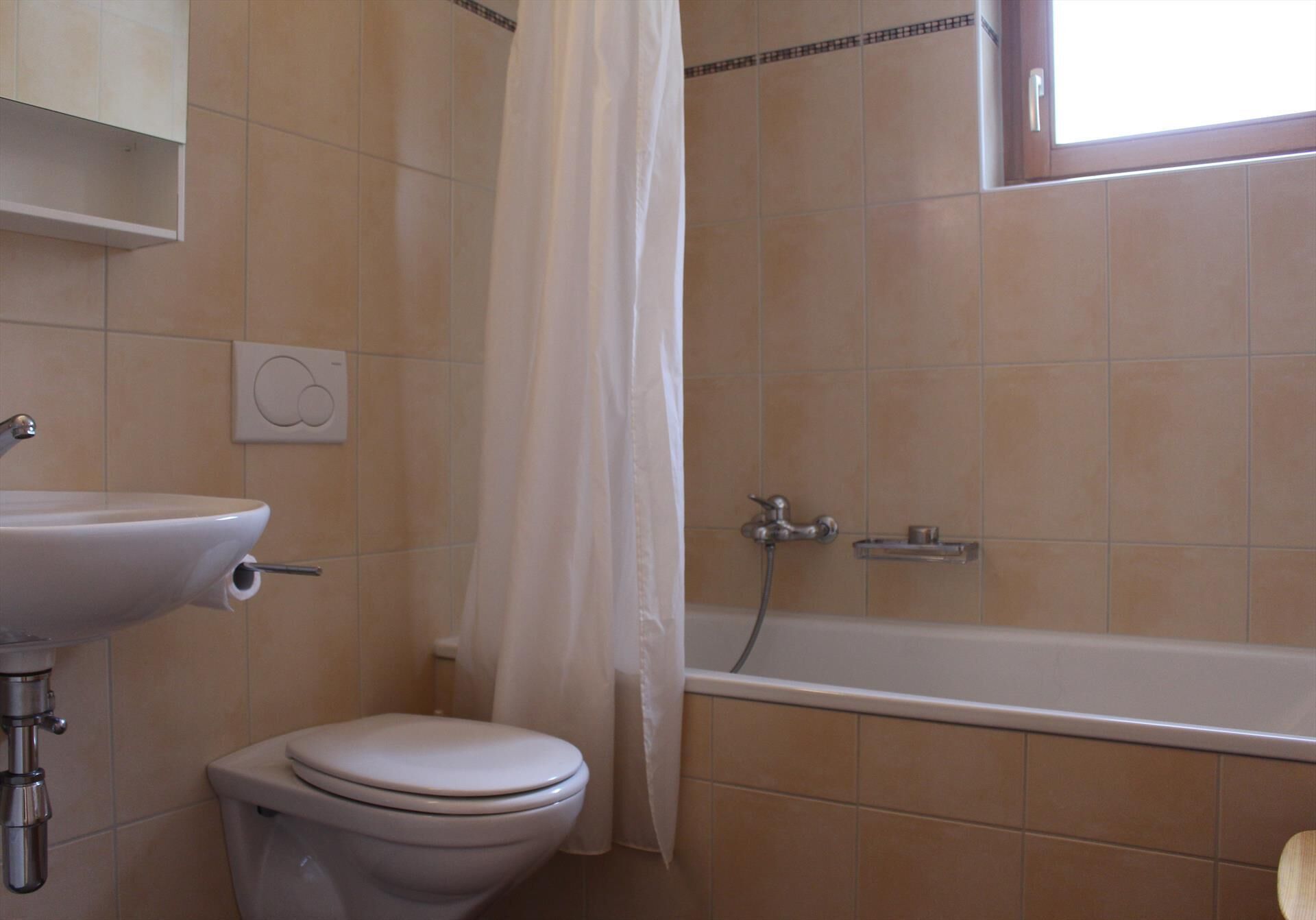 Et badeværelse med toilet, vask og badekar.