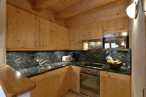 Eine Küche mit Holzschränken, Granit-Arbeitsplatten und Edelstahlgeräten, sowie einer Obstschale.