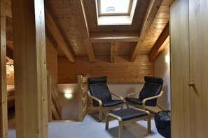 Ein Holzinnenraum mit zwei schwarzen Stühlen, einem Oberlicht und einer Holztreppe.