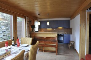 Ein Holzkaminzimmer mit Essbereich, Küche und großen Fenstern.